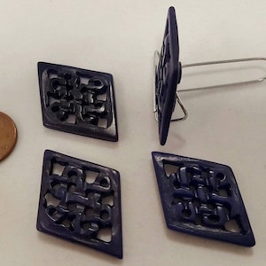 May include: Four dark blue diamond-shaped buttons with intricate carved designs. The buttons have a glossy finish and are made of a hard plastic material.