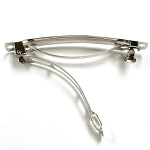 May include: A silver metal hair clip with a curved shape and a spring-loaded clasp.