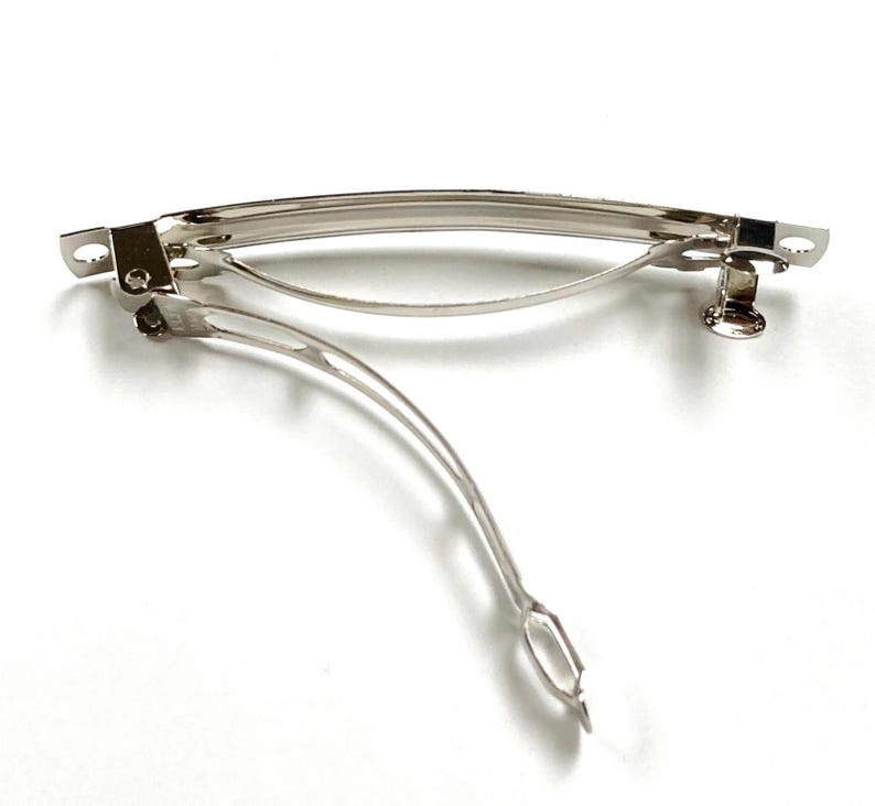 May include: A silver metal hair clip with a curved shape and a spring-loaded clasp.