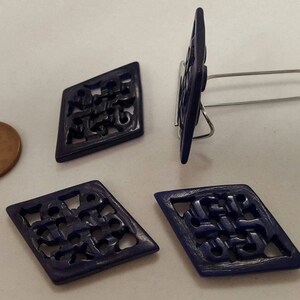 May include: Four dark blue diamond-shaped buttons with intricate cut-out designs. The buttons have a matte finish and are made of a hard plastic material.