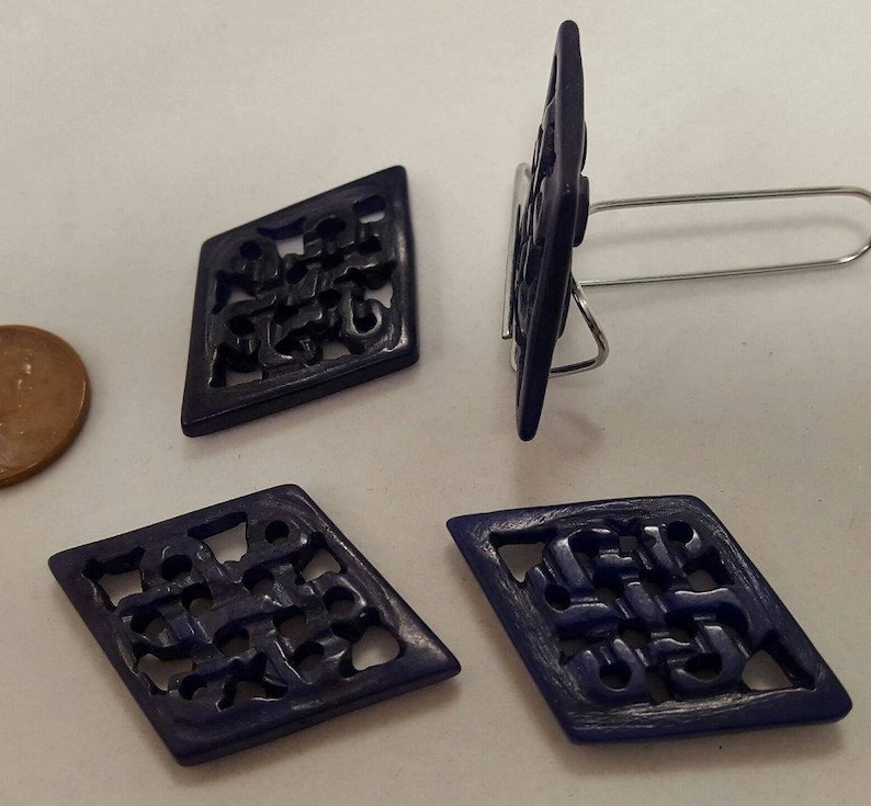 May include: Four dark blue diamond-shaped buttons with intricate cut-out designs. The buttons have a matte finish and are made of a hard plastic material.