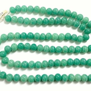 May include: A strand of green jade beads with a white label that reads "M JAPAN".