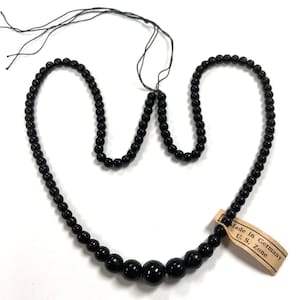 May include: A black beaded necklace with a tag that reads "Made in Germany U.S. Zone".