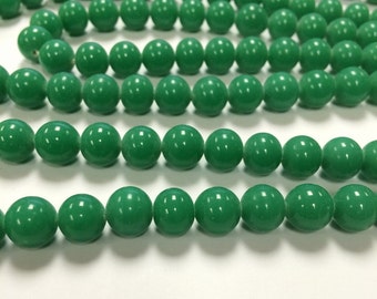 May include: A strand of bright green round beads. The beads are smooth and glossy.