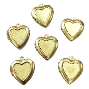 May include: Six antique brass-colored heart-shaped lockets. Each locket has a hinged opening and a small loop at the top for attaching to a chain or other jewelry. The lockets have a vintage, aged appearance.