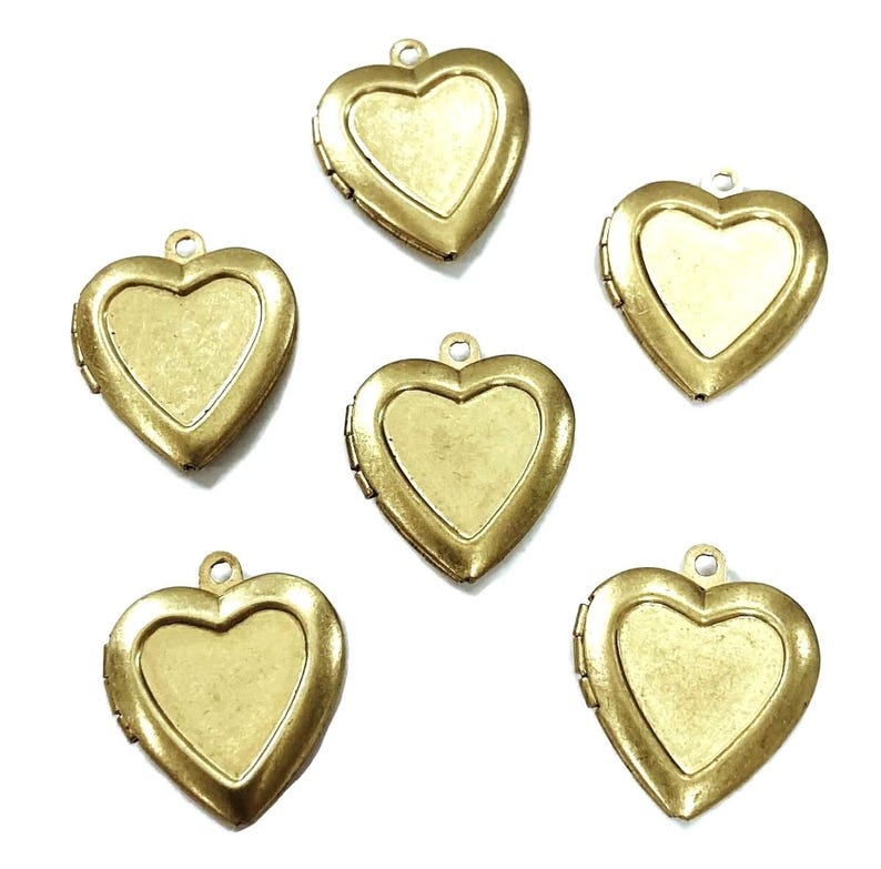 May include: Six antique brass-colored heart-shaped lockets. Each locket has a hinged opening and a small loop at the top for attaching to a chain or other jewelry. The lockets have a vintage, aged appearance.