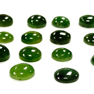 May include: A collection of thirteen smooth, polished, round, and oval-shaped green gemstones. Each stone features a domed cabochon cut with a glossy, reflective surface, displaying various shades of deep forest green and lighter translucent emerald tones.