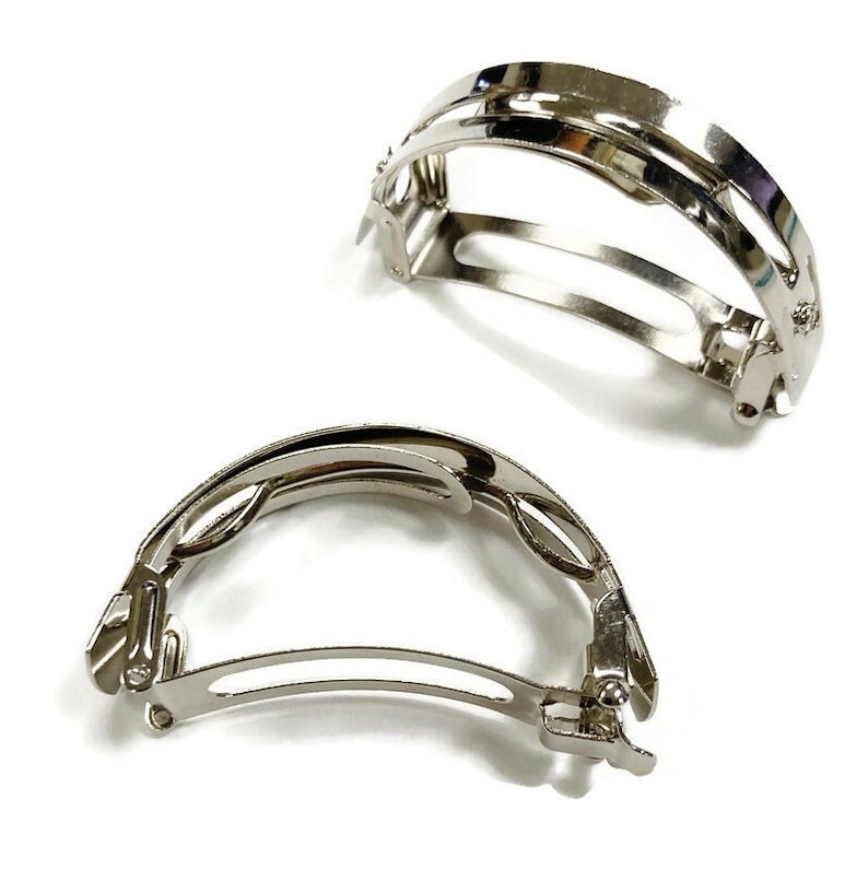 May include: Two silver metal hair clips. The clips are curved and have a smooth, shiny finish.