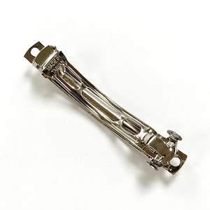 May include: A silver metal hair clip with a curved shape and a spring-loaded clasp. The clip is marked "MADE IN TAIWAN".