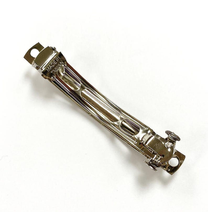 May include: A silver metal hair clip with a curved shape and a spring-loaded clasp. The clip is marked "MADE IN TAIWAN".