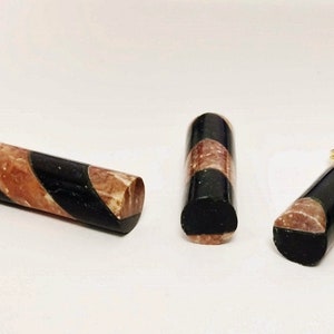 May include: Three black and brown striped cylindrical pendants with gold accents. The pendants are made of a marbled material.