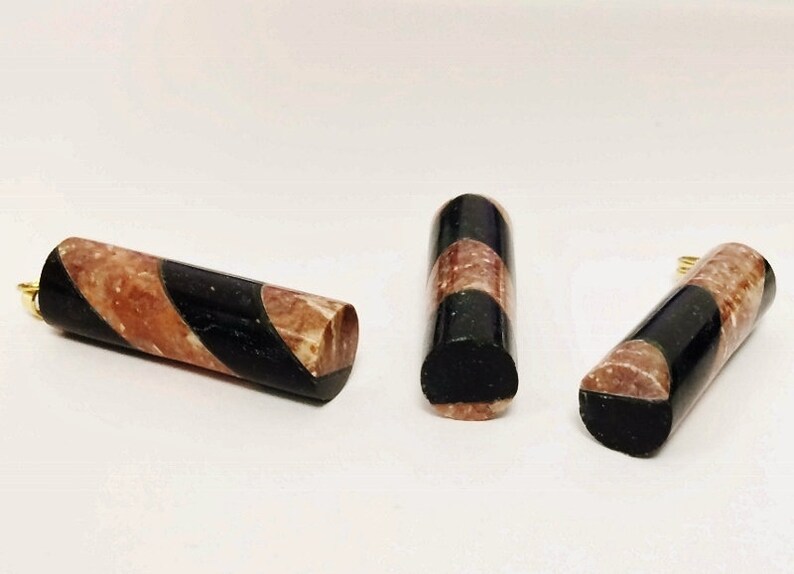 May include: Three black and brown striped cylindrical pendants with gold accents. The pendants are made of a marbled material.