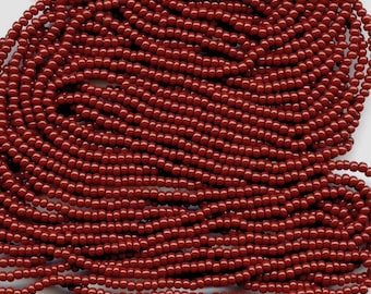 May include: A strand of small, round, red beads. The beads are uniform in size and shape, and they are arranged in a close-packed pattern.