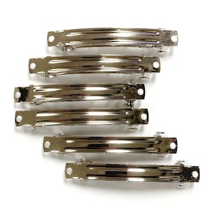 May include: Six silver metal hair clips, each with a smooth, curved design. The clips are arranged in a row, with the largest clip at the top and the smallest clip at the bottom.