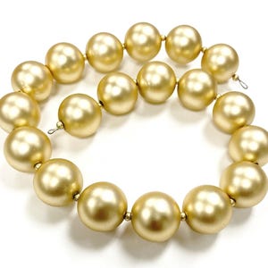 May include: A strand of large, golden, round beads. The beads are strung on a wire and have a smooth, shiny finish.