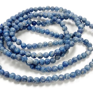 May include: A strand of blue and white marbled round beads. The beads are strung together on a clear thread.