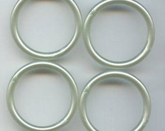 May include: Four translucent, light green rings arranged in a square. Each ring is a complete circle, with a smooth, rounded surface. The rings appear to be made of a clear, possibly plastic material. The overall aesthetic is simple and clean.