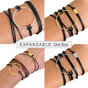 May include: Expandable bracelets with a circular design. The bracelets feature black leather cords and silver or gold-colored metal accents. The text "EXPANDABLE. One Size" is displayed in a white rectangle.