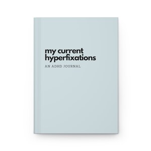 May include: A light blue journal with the text "my current hyperfixations" and "AN ADHD JOURNAL" in black.