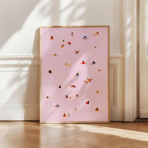 May include: A framed print with a pink background and a pattern of small, colorful figures in various poses. The figures appear to be swimming or floating in the water.