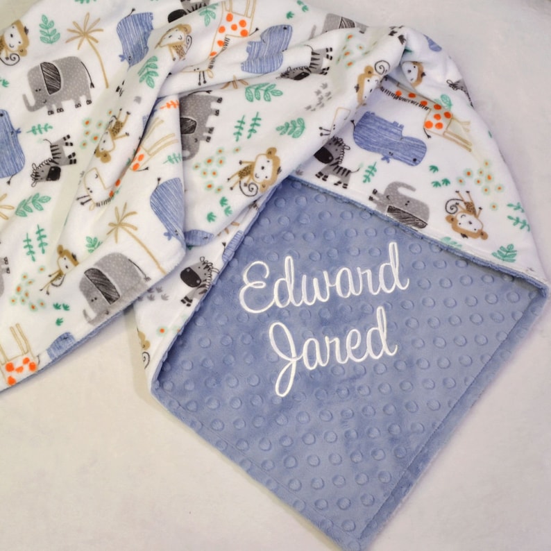 handmade baby blanket with a jungle minky print, featuring elephants, hippos, monkeys, zebras and giraffes, and a dimple textured minky with embroidered personalization.