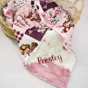 May include: A pink and white baby blanket with a cow print design and the text "Though she be but little, she is fierce." The blanket is personalized with the name "Presley" in red embroidery.