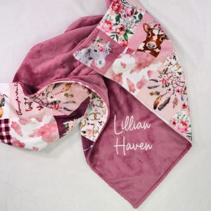 May include: A pink and white patchwork baby blanket with a floral and animal print. The blanket is personalized with the name "Lillian Haven".