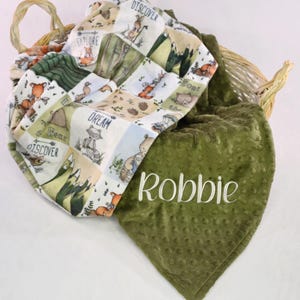 May include: A green and white baby blanket with a woodland animal print and the name "Robbie" embroidered on the green side.