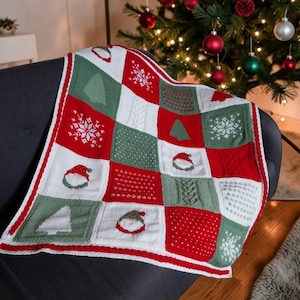 May include: A knitted throw blanket featuring a patchwork design of red, white, and green squares. The pattern includes motifs of Christmas trees, snowflakes, and gnomes with red hats, interspersed with textured cable knit and dotted square panels.
