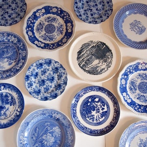 Puede incluir: Una colección de diez platos de cerámica con varios patrones en azul y blanco, incluyendo motivos florales, escenas de paisajes y bordes geométricos intrincados. Los platos varían en tamaño y detalle, algunos con bordes festoneados.