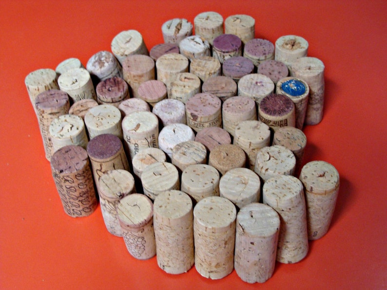 May include: A close-up of a cork trivet made from wine corks. The corks are arranged in a circular pattern with a few corks in the center. The trivet is a light brown color and has a natural, rustic look.
