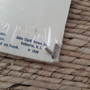 May include: Close-up of a white label with the text "John Clark Brown, Inc. Belleville, N.J. &copy; 1959" printed on it.