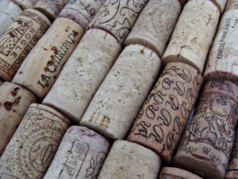 May include: A close-up of a collection of wine corks with various labels and designs. The corks are made of natural cork and have a variety of colors and textures. Some of the corks have text on them, including "LA CHIRIPADA", "BOGLE", "CONCHAY TORO", and "ST11".