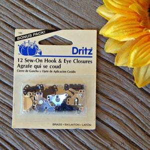 May include: A package of 12 sew-on hook and eye closures in brass. The package is labeled "Dritz" and says "Bonus Pack!"