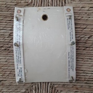 May include: White card with instructions for using a spring adjustment for picture hanging wire. The card has a hole in the center and text that reads "For plates over 7 1/2" use side er platters over 11" discard spring. Clips as illustrated. Clips with this spring adjustment use picture hanging wire to attach Patent No. 2,826,384 Made in U.S.A. John Clark Brown, Inc. Belleville, N.J. 1959"