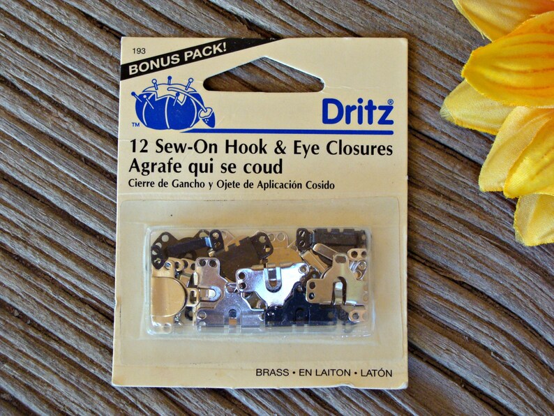 May include: A package of 12 sew-on hook and eye closures in brass. The package is labeled "Dritz" and "Bonus Pack!" with the text "12 Sew-On Hook & Eye Closures" and "Agrafe qui se coud".