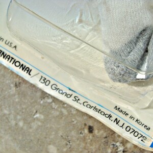 May include: Close-up of a white and blue packaging label with the text "Printed in U.S.A. Made in Korea EZ INTERNATIONAL/ 130 Grand St.. Carlstadt. N.J. 07072"