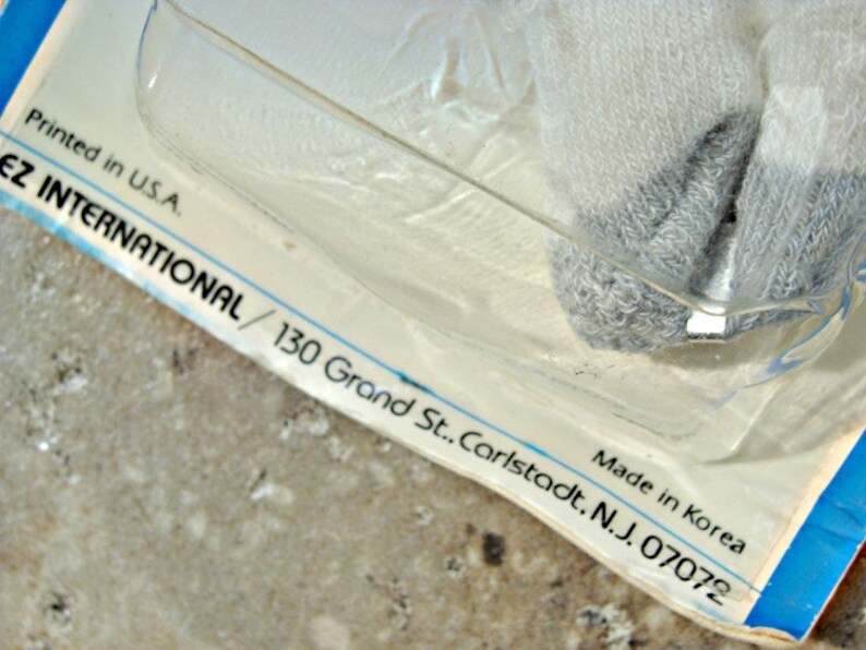 May include: Close-up of a white and blue packaging label with the text "Printed in U.S.A. Made in Korea EZ INTERNATIONAL/ 130 Grand St.. Carlstadt. N.J. 07072"