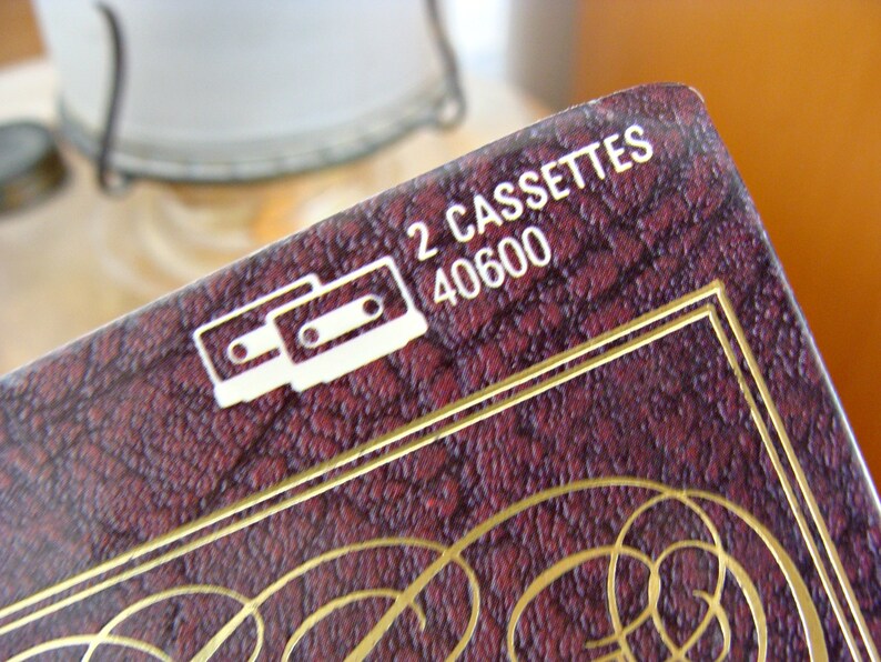May include: Close-up of a burgundy box with gold trim and text. The box features the words "2 CASSETTES" and the number "40600" in white. A white graphic of two cassette tapes is also visible.