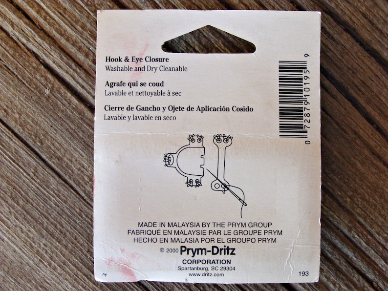 May include: A white package with black text and a barcode. The text reads "Hook & Eye Closure Washable and Dry Cleanable Agrafe qui se coud Lavable et nettoyable &agrave; sec Cierre de Gancho y Ojete de Aplicaci&oacute;n Cosido Lavable y lavable en seco Made in Malaysia by the Prym Group Fabriqu&eacute; en Malaysie par le Groupe Prym Hecho en Malasia por el Grupo Prym &copy; 2000 Prym-Dritz Corporation Spartanburg, SC 29304 www.dritz.com 193".