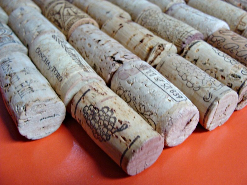 May include: A close-up of a pile of wine corks, some with the text "Concha y Toro" printed on them. The corks are arranged in a row on a bright orange surface.