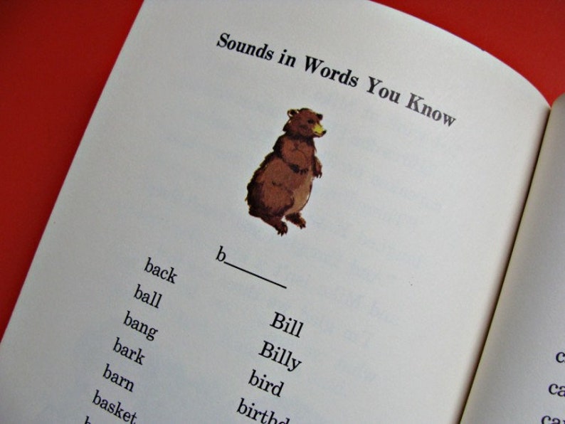 Może przedstawiać: Otwarta strona książki z tytułem "Sounds in Words You Know". Ilustracja brązowego niedźwiedzia znajduje się nad listą sł&oacute;w zaczynających się na literę "b". Słowa obejmują "back", "ball" i "bang".