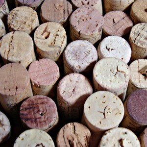 May include: A close-up of a collection of cork bottle stoppers in various shades of brown and beige. The corks are arranged in a random pattern, creating a textured and natural look.