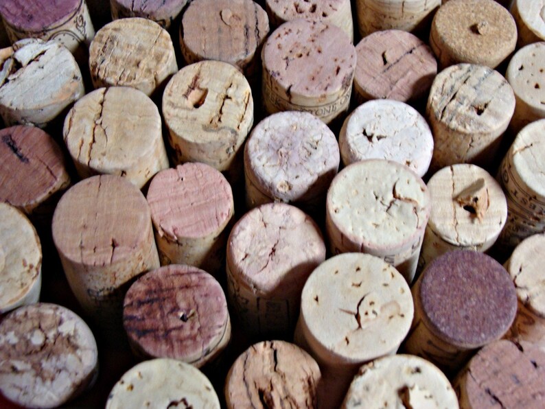 May include: A close-up of a collection of cork bottle stoppers in various shades of brown and beige. The corks are arranged in a random pattern, creating a textured and natural look.