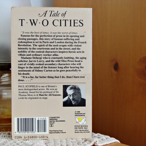 May include: A Tale of Two Cities audiobook cassette case. The cover displays the title in a classic font. The back includes a synopsis, author details, and a photo of Paul Scofield. The case is a vintage item.