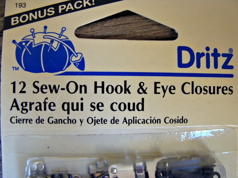 May include: A package of 12 sew-on hook and eye closures. The package is labeled "Dritz" and includes the text "12 Sew-On Hook & Eye Closures, Agrafe qui se coud, Cierre de Gancho y Ojete de Aplicaci&oacute;n Cosido".