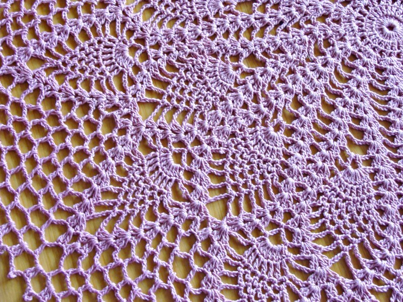 May include: A close-up of a purple crocheted doily with a delicate, intricate pattern.