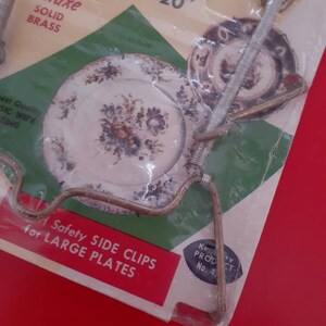 May include: A package of two brass plate clips for holding large plates. The package says "Fits all sizes 5" to 20" Deluxe Solid Brass" and "Safety Side Clips for Large Plates".