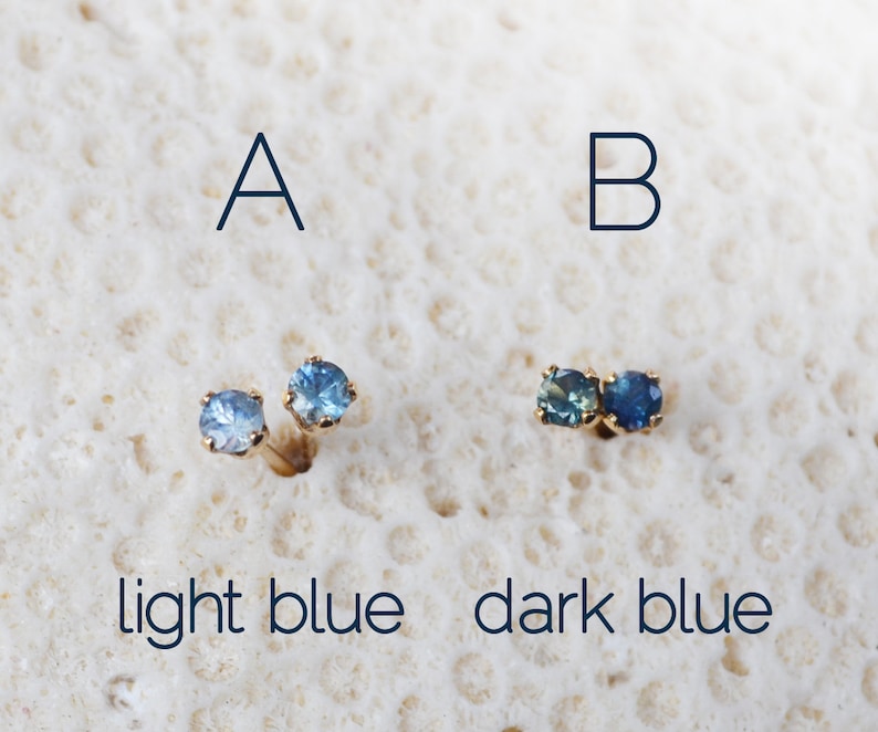 Puede incluir: Dos pares de pendientes de bot&oacute;n con piedras preciosas redondas azules. Los pendientes de la izquierda son de un azul m&aacute;s claro, etiquetados como "A azul claro". Los pendientes de la derecha son de un azul m&aacute;s oscuro, etiquetados como "B azul oscuro".