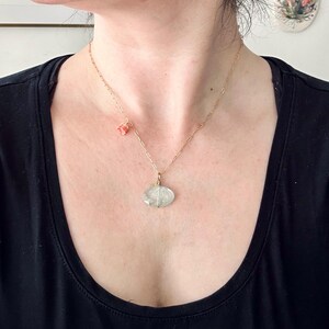 May include: A gold chain necklace with a light blue oval pendant and a small pink flower charm.